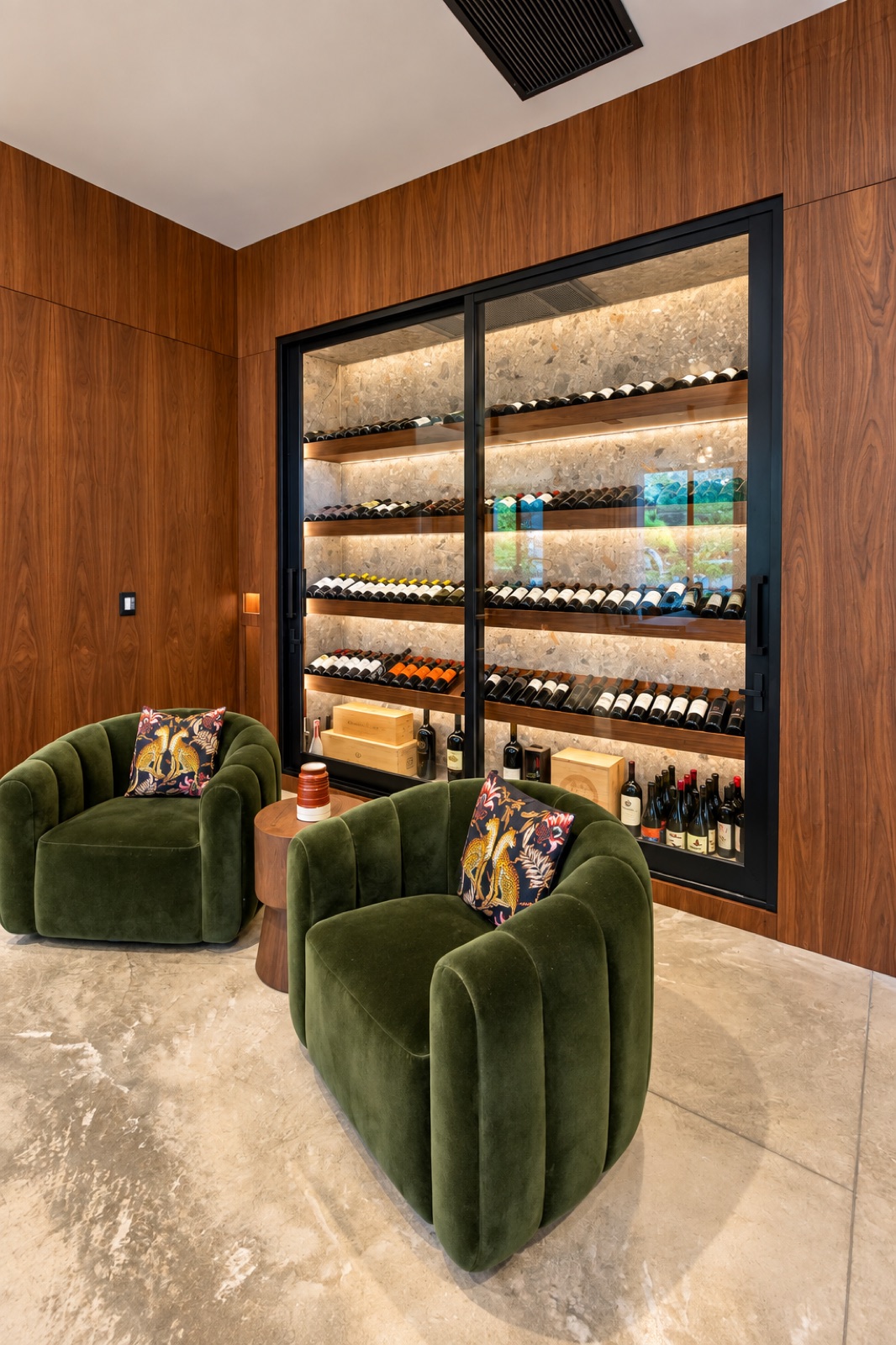 Tampa home wine display with illuminated shelves behind black-framed glass, surrounded by walnut paneling